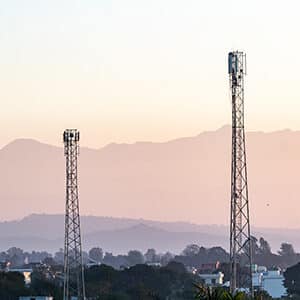 cell towers surrounded with houses and trees near the mountains